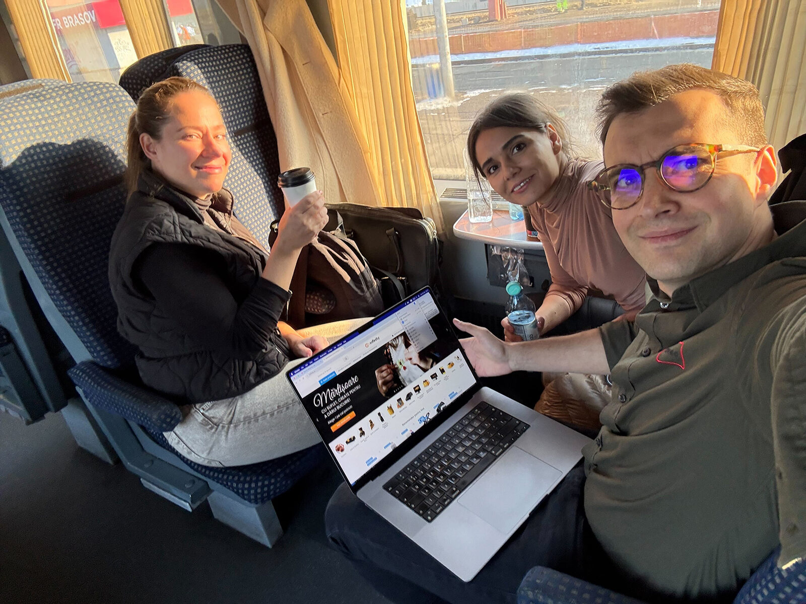 Three of the ivi.works team on a train, reviewing a client storefront on a laptop
